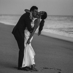 a bride and groom kissing on the beach