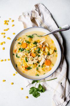 a bowl of soup with chicken, carrots and parsley in it on a white surface