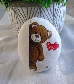 a teddy bear painted on a rock next to a potted plant