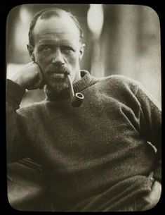 an old photo of a man with a pipe in his mouth and wearing a sweater