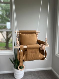 a wooden swing chair hanging from a ceiling in a room with a potted plant