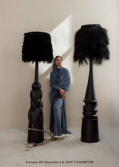 a woman standing next to three black lamps