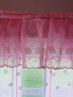 the pink curtains are hanging in front of the window sill with flowers on it