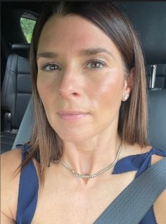 a woman wearing a blue dress sitting in the back seat of a car looking at the camera