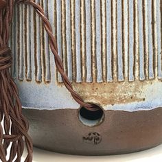 a close up of a vase with a tassel on the side and a brown cord hanging from it