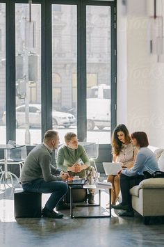 group of people sitting around a table with laptops