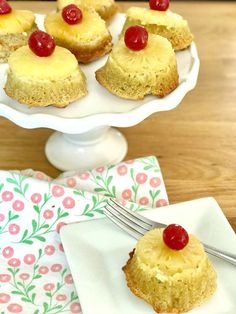 pineapple cupcakes with cherries on top are sitting on a white plate