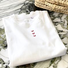 Oversized white T-shirt marked with little red hearts, it's up to you to choose the number :-) They are made and printed in France (in Roubaix and Tourcoing) and woven in a pretty eco-responsible Greek cotton jersey. Prints are made piece by piece to order. The LOW IMPACT® Label guarantees a QUALITY product and LOCAL-SUSTAINABLE-SOCIAL manufacturing in an approach of JOB CREATION, SOLIDARITY and RE-LOCALIZATION. COLORS: white jersey with red print SIZES: Our T-Shirts are unisex and oversized, so White Relaxed Fit T-shirt With Heart Graphic, Red Cotton T-shirt With Heart Print, White Graphic Tee For Valentine's Day, White Cotton T-shirt With Heart Print, White Cotton T-shirt For Valentine's Day, White Tops With Heart Graphic For Valentine's Day, White T-shirt For Valentine's Day Gift, Cute White T-shirt For Valentine's Day, Cotton Tops With Heart Print As A Gift