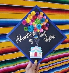 someone is holding up a graduation cap that has flowers on it and the words adventure is out there