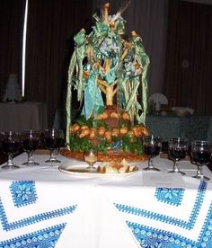 a table topped with a cake covered in frosting next to wine glasses and napkins