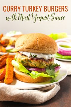 a turkey burger on a white plate with lettuce and tomato wedges next to it