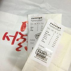 receipt sitting on top of a white bag with red letters and numbers written in it