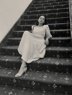 a woman sitting on some stairs with her legs crossed and looking up at the sky