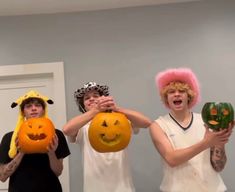 three young men holding pumpkins with faces painted on them