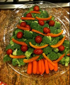 a christmas tree made out of carrots and broccoli on a clear plate