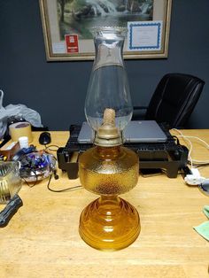 a glass lamp sitting on top of a wooden table next to a laptop computer and other office supplies