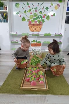 two young children sitting on the floor in front of baskets filled with vegetables