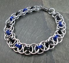 "This awesome chainmaille bracelet was hand woven in the Helm/Parallel weave using shiny silver and anodized aluminum rings, with grape purple and black accent rings. This piece is actually quite light due to the materials used to craft it. Wrist Size: 6 1/2\" to 7\" (shown on 7\" wrist in 5th picture) Colors: Bright Silver, Grape Purple, Black Materials: Bright Aluminum, Anodized Aluminum Clasp: Stainless Steel Lobster Clasp You can check out my other chainmaille bracelets here: https://www.ets Black Stainless Steel Chainmail Jewelry, Chainmail Jewelry, Chainmaille Bracelet, Black Accents, Shiny Silver, Chain Link Bracelet, Purple And Black, Silver Bracelet, Chain Necklace