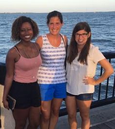 three women standing next to each other near the water