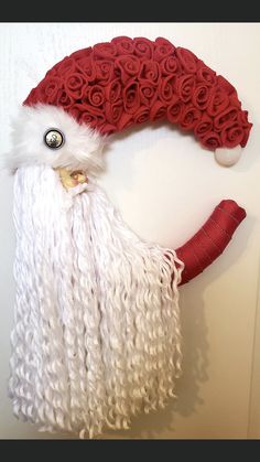 a red and white santa claus hat on top of a door handle with roses attached to it