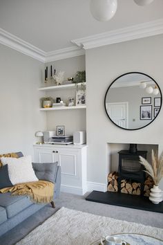 a living room filled with furniture and a fire place under a round mirror on the wall