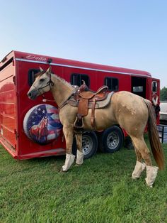 a horse standing next to a trailer with an american flag painted on it's side