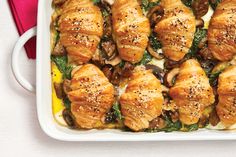 a casserole dish filled with chicken wrapped in spinach and mushrooms, garnished with sesame seeds