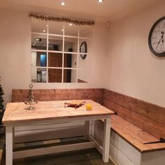 a wooden bench sitting in front of a window next to a clock on the wall