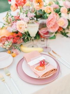 the table is set with pink plates, silverware, and flowers on it for an elegant wedding reception