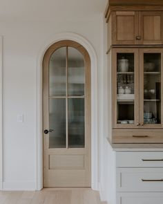 an empty kitchen with wooden cabinets and white cupboards on either side of the door