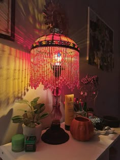 a lamp that is sitting on top of a table next to some plants and candles