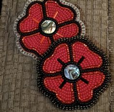 two red and black beaded brooches sitting on top of a piece of cloth