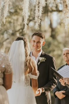 the bride and groom are exchanging vows at their wedding ceremony in front of an old oak tree