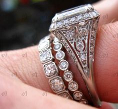 a close up of a person's hand holding a ring with diamonds on it