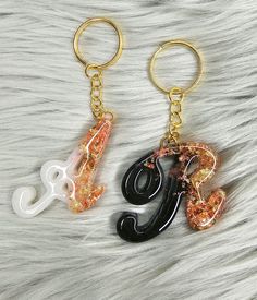 two key chains with letters on them sitting on top of a white fur covered surface