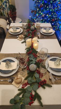 the table is set for christmas dinner with candles, plates and napkins on it