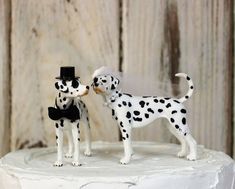 a cake topper that has two dogs on it, one is kissing the other