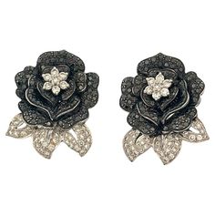 This early 20th-century rose-shaped black and white diamond earring is a striking testament to the elegance and craftsmanship of the era. It features a white diamond at center , radiating brilliance and serving as the heart of a beautifully designed rose. Surrounding this center are meticulously arranged black diamonds that resemble the petals of a blooming rose, creating a stunning contrast. Adding to the intricate artistry, the 'petals' themselves are crafted from white diamonds, enhancing the Luxury Diamond White Earrings With Rose Cut Diamonds, Elegant White Diamond Flower-shaped Earrings, Luxury Rose Cut Diamond Chandelier Earrings, Luxury Diamond-cut Flower-shaped Earrings, Luxury Black Flower-shaped Jewelry, White Diamond Earrings, Blooming Rose, Art Deco Earrings, Rose Petals