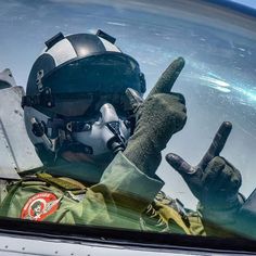 a pilot in the cockpit of an airplane with his hand up and pointing at something