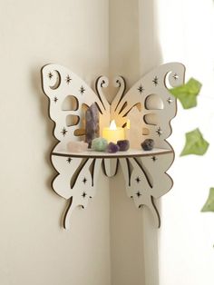 a candle that is sitting on a shelf next to a butterfly shaped wall mounted decoration