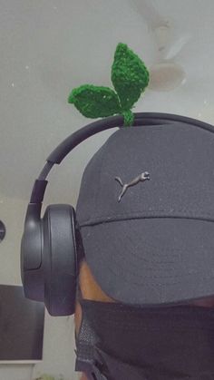 a man wearing headphones and a hat with a green leaf on top of it