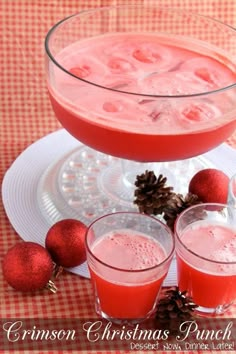 two glasses filled with liquid sitting on top of a plate next to pine cones and ornaments