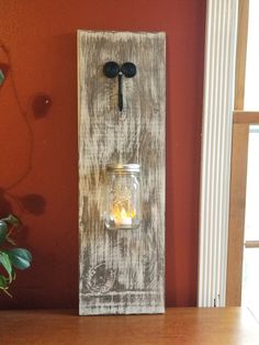 a mason jar is mounted to a wall with a candle holder on the front and side