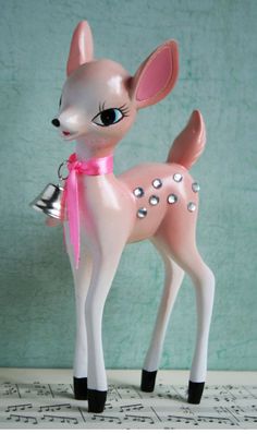 a small toy deer with a bell on its neck and pink bow around its neck