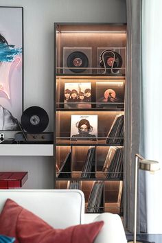 a white couch sitting in front of a book shelf filled with vinyl records