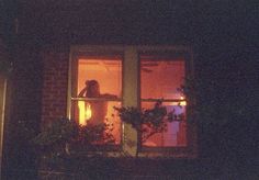 a woman is looking out the window at night