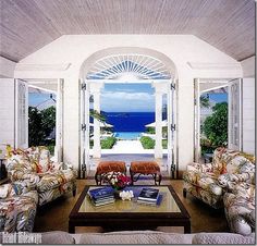 a living room filled with lots of furniture next to an open door leading to the ocean