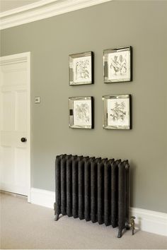 four framed pictures hang on the wall above a radiator in a living room