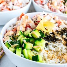 three bowls filled with rice, cucumber and other food on top of a table