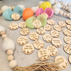 wooden name tags with tassels and string on top of a table next to balloons